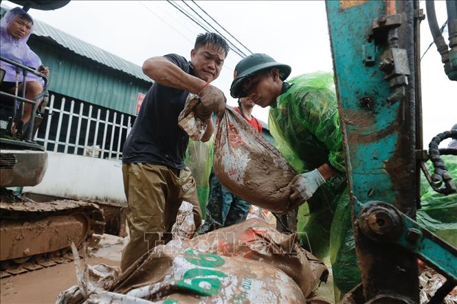 Quân và dân đồng sức, đồng lòng ngăn lũ tràn qua đê. Ảnh: Minh Quyết - TTXVN