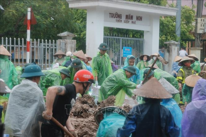Chiến sĩ Trung đoàn 102 và người dân chuẩn bị bao tải đất để gia cố đê sông Tích, ngăn nước tràn qua đê. Ảnh: Minh Quyết - TTXVN
