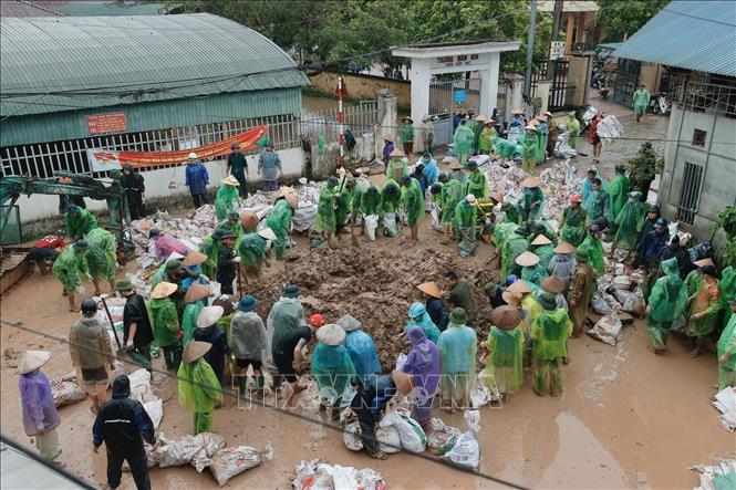 Người dân và chiến sĩ Trung đoàn 102 hợp sức nỗ lực đối phó với lũ lụt. Ảnh: Minh Quyết - TTXVN