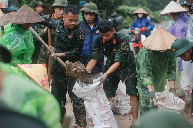 Quân đội và người dân quyết tâm ngăn không để nước tràn qua đê. Ảnh: Minh Quyết - TTXVN