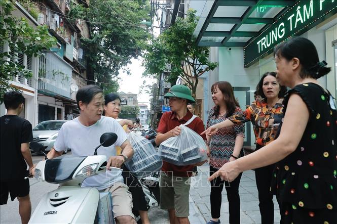 Lực lượng gồm cựu chiến binh, hội chữ thập đỏ, hội phụ nữ… cùng chung tay hỗ trợ, mang cơm đến chỗ ở của các hộ tạm tránh lũ. Ảnh: Minh Quyết - TTXVN