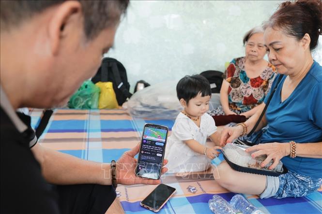 Người dân tranh thủ cập nhật thông tin về thời tiết. Ảnh: Minh Quyết - TTXVN