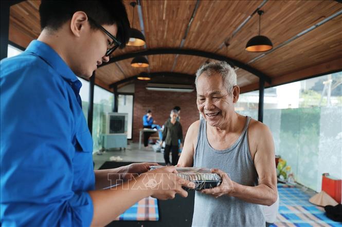 Lực lượng đoàn viên phường Chương Dương hỗ trợ phát cơm đến với người dân đang tạm trú ở nơi an toàn. Ảnh: Minh Quyết - TTXVN