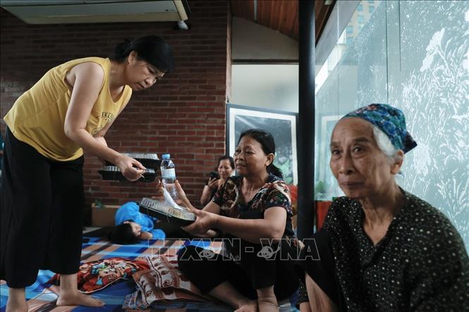 Cán bộ Hội Chữ thập phường Chương Dương phát cơm cho người dân đang tránh lũ. Ảnh: Minh Quyết - TTXVN