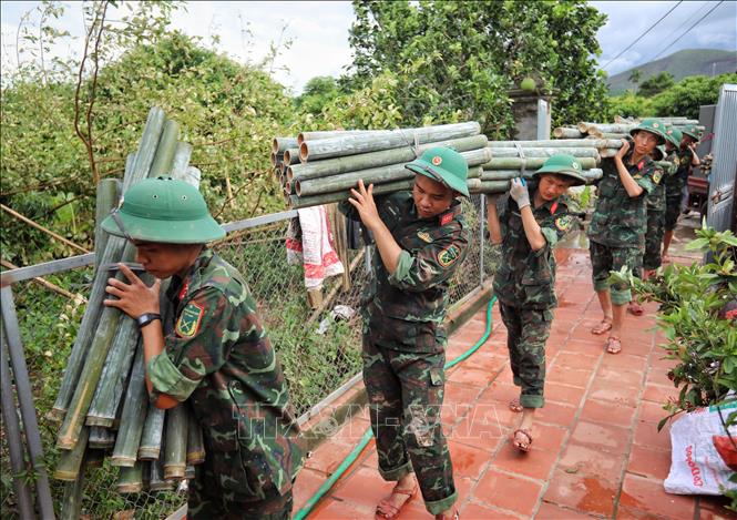 Cán bộ, chiến sĩ Sư đoàn 325 giúp dân vận chuyển đồ đạc tại thôn Khả Lã, xã Tân Lập, huyện Lục Ngạn. Ảnh: Danh Lam - TTXVN