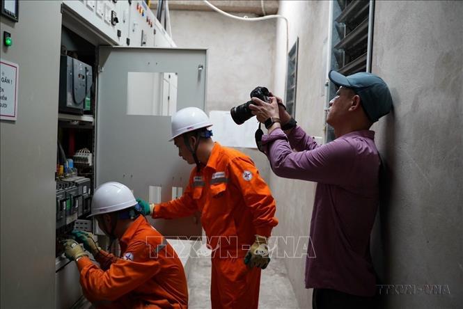 Phóng viên Huy Hùng (Ban Biên tập Ảnh) tác nghiệp tại trạm biến áp của 1 khu chung cư tại quận Hoàng Mai (Hà Nội) trong đợt thiếu điện 6/2023. Ảnh: TTXVN