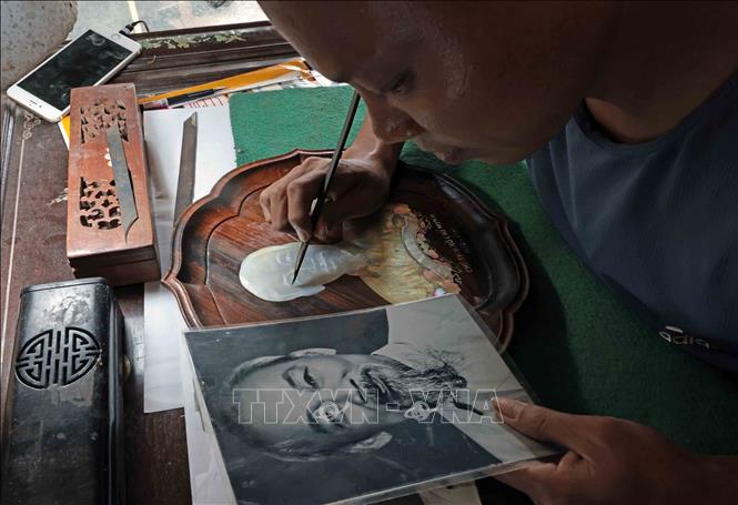 Artisan Nguyen Dinh Hieu paints President Ho Chi Minh’s portrait on a nacre piece. VNA Photo: Trần Việt