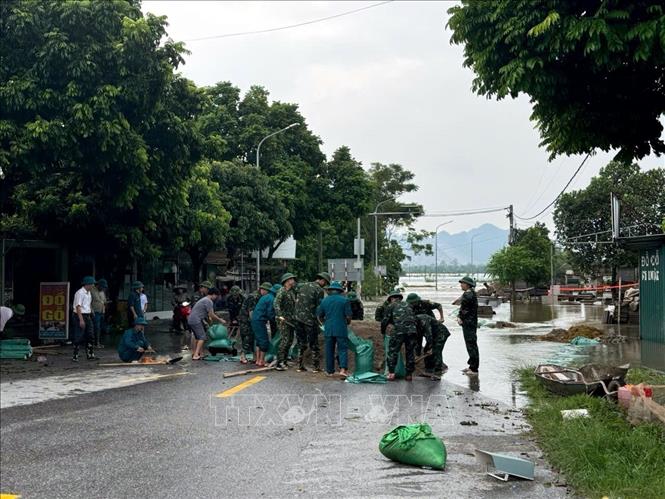 Lượng chức năng xã và huyện Ứng Hòa đang tập trung ứng phó, đắp tải cát để bảo vệ những điểm xung yếu tại đập tràn Dốc Bồ. Ảnh: Nguyễn Văn Cảnh-TTXVN