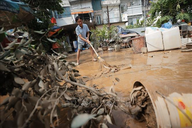Người dân dọn dẹp sau khi nước rút (ảnh chụp lúc 9h22). Ảnh: Minh Quyết - TTXVN
