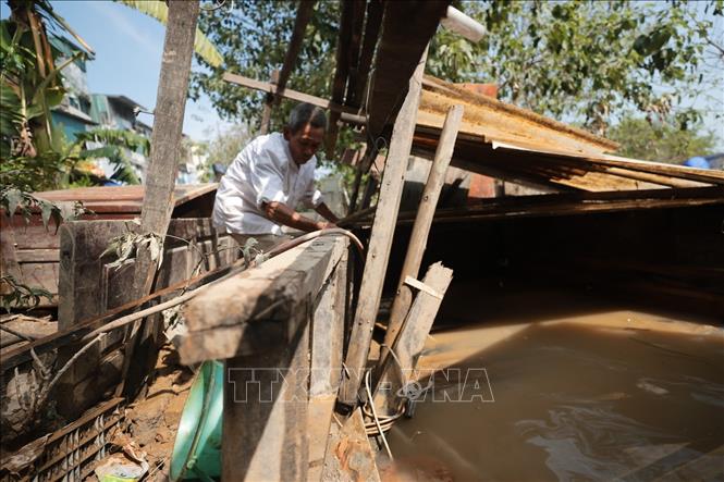 Một người dân sửa lại chuồng gà bị nước ngập làm hỏng (ảnh chụp lúc 9h14). Ảnh: Minh Quyết - TTXVN