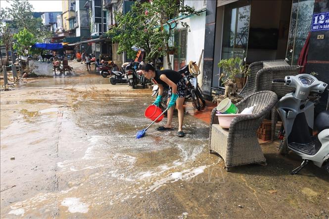 Người dân phường Phúc Tân, quận Hoàn Kiếm dọn dẹp vệ sinh nhà cửa sau khi nước rút (ảnh chụp lúc 10 giờ 5 phút). Ảnh: Tuấn Anh - TTXVN
