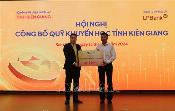 Ông Nguyễn Văn Thùy (trái), đại diện HĐQT Ngân hàng TMCP Lộc Phát Việt Nam, trao bảng tượng trưng ủng hộ Quỹ Khuyến học tỉnh Kiên Giang. Ảnh: Lê Huy Hải - TTXVN