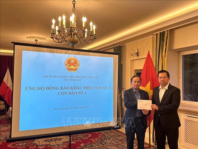 Đại sứ Hà Hoàng Hải (phải) trao cho ông Trần Anh Tuấn, Chủ tịch Hội người Việt Nam tại Ba Lan số tiền ủng hộ đồng bào khắc phục hậu quả cơn bão số 3. Ảnh: TTXVN phát