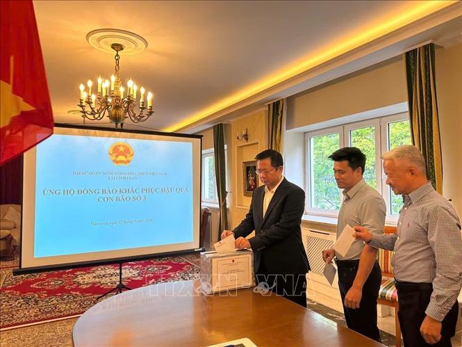 Cán bộ, nhân viên Đại sứ quán Việt Nam tại Ba Lan quyên góp ủng hộ đồng báo khắc phục hậu quả của cơn bão số 3. Ảnh: TTXVN phát