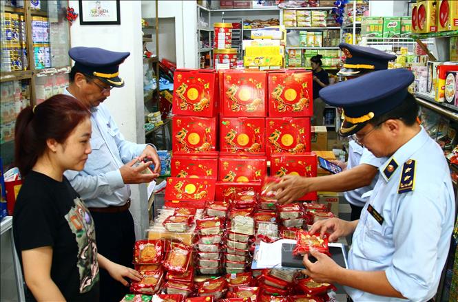 Cán bộ Cục Quản lý thị trường tỉnh Quảng Bình kiểm tra nguồn gốc xuất xứ mặt hàng bánh Trung thu. Ảnh: Tá Chuyên - TTXVN