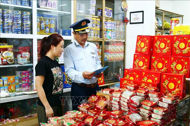 Cán bộ Cục Quản lý thị trường tỉnh Quảng Bình tuyên truyền đến các cơ sở kinh doanh thực hiện nghiêm quy định về buôn bán các mặt hàng dịp Tết Trung thu. Ảnh: Tá Chuyên - TTXVN