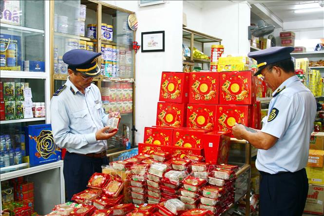 Cán bộ Cục Quản lý thị trường tỉnh Quảng Bình kiểm tra nguồn gốc xuất xứ mặt hàng bánh Trung thu. Ảnh: Tá Chuyên - TTXVN