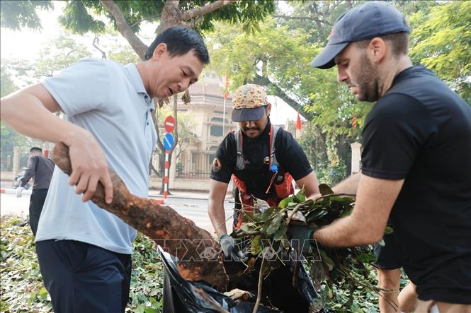 Tình nguyện viên cùng chung tay dọn dẹp, vệ sinh môi trường, khắc phục hậu quả bão số 3 tại khu vực quận Hoàn Kiếm. Ảnh: Minh Quyết - TTXVN