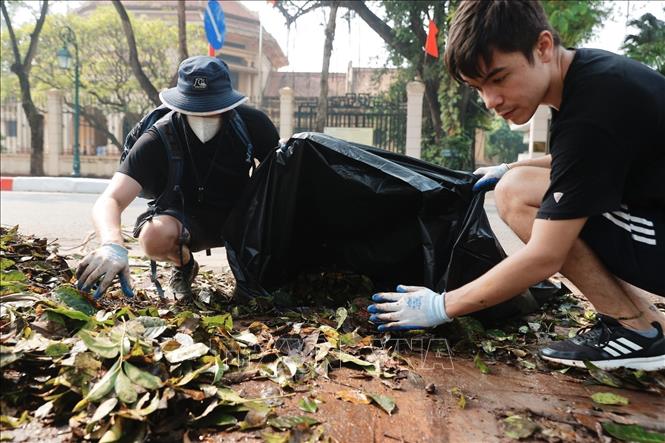 Tình nguyện viên thu gom rác tại khu vực vườn hoa Bác Cổ (quận Hoàn Kiếm). Ảnh: Minh Quyết - TTXVN