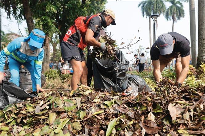 Tình nguyện viên thu gom rác tại khu vực vườn hoa Bác Cổ (quận Hoàn Kiếm). Ảnh: Minh Quyết - TTXVN