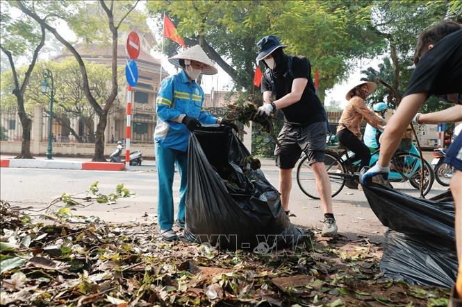 Tình nguyện viên thu gom rác tại khu vực vườn hoa Bác Cổ (quận Hoàn Kiếm). Ảnh: Minh Quyết - TTXVN