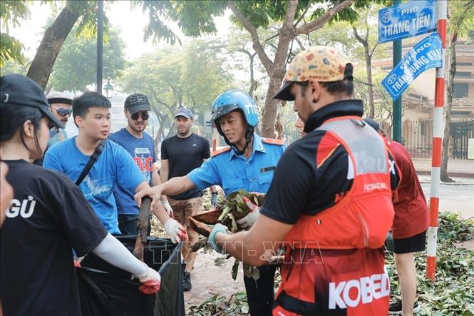 Tình nguyện viên nước ngoài chung tay cùng các lực lượng dọn dẹp, vệ sinh môi trường tại khu vực quận Hoàn Kiếm. Ảnh: Minh Quyết - TTXVN