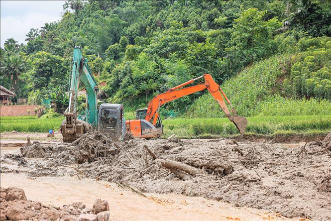 Máy xúc, máy đào được huy động để tìm kiếm tại những vị trí khả năng có nạn nhân. Ảnh: Hoàng Hiếu - TTXVN