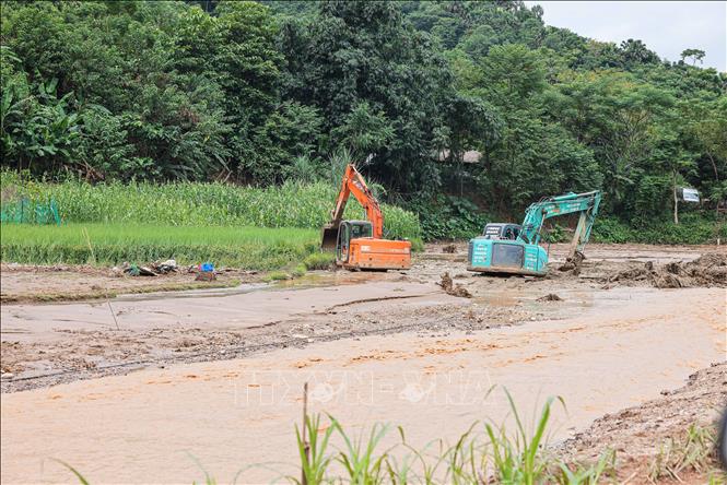 Máy xúc, máy đào được huy động để tìm kiếm tại những vị trí khả năng có nạn nhân. Ảnh: Hoàng Hiếu - TTXVN