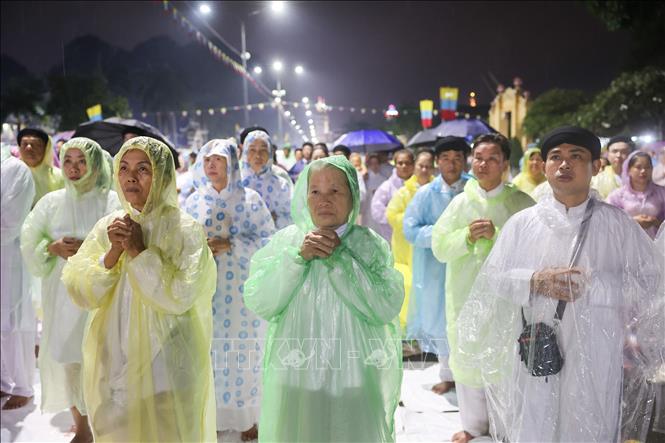 Người dân đội áo mưa cầu cho mưa thuận gió hòa, quốc thái dân an tại lễ Hội yến Diêu Trì Cung lúc 22 giờ. Ảnh: Giang Phương - TTXVN