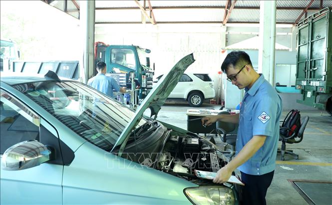 Các đăng kiểm viên kiểm tra phương tiện tại Trung tâm đăng kiểm 2401D. Ảnh: Quốc Khánh - TTXVN