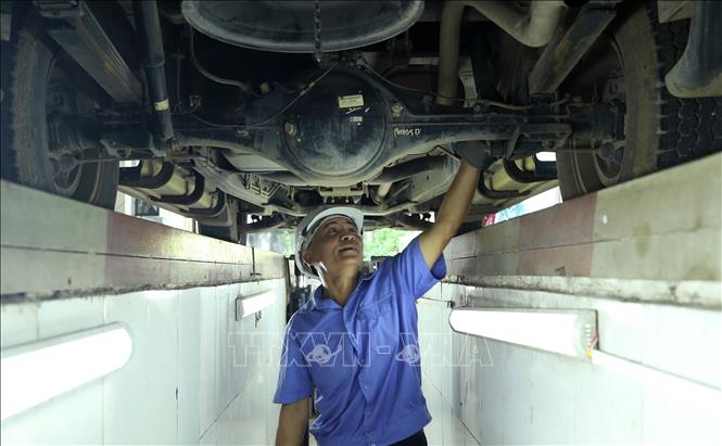 Các đăng kiểm viên kiểm tra phương tiện tại Trung tâm đăng kiểm 2401D. Ảnh: Quốc Khánh - TTXVN