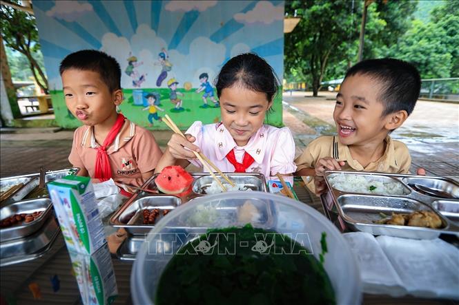 Trong không khí vui vẻ và ấm áp, các học sinh xóm Rằng ăn suất cơm trưa bán trú ngon miệng và no nê. Ảnh: Trọng Đạt-TTXVN