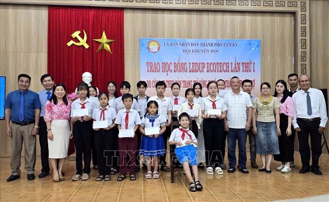 Đại diện nhà tài trợ cùng lãnh đạo Hội Khuyến học thành phố Tam Kỳ chụp ảnh lưu niệm với các học sinh được nhận học bổng. Ảnh: Trịnh Bang Nhiệm - TTXVN