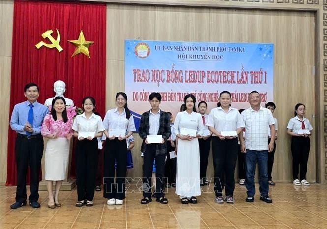 Đại diện nhà tài trợ cùng lãnh đạo Hội Khuyến học thành phố Tam Kỳ trao học bổng cho các học sinh. Ảnh: Trịnh Bang Nhiệm - TTXVN
