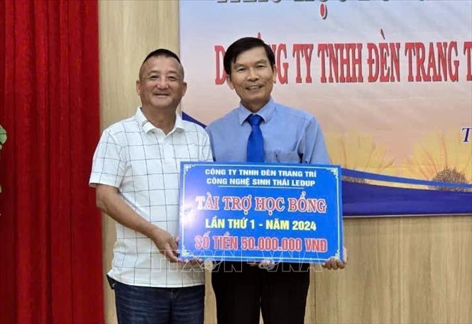 Đại diện nhà tài trợ trao tặng bảng học bổng có tổng trị giá 50 triệu đồng cho lãnh đạo Hội Khuyến học thành phố Tam Kỳ. Ảnh: Trịnh Bang Nhiệm - TTXVN
