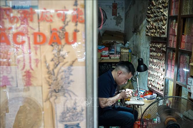 Trong cửa hiệu nhỏ trên phố Hàng Quạt, với vài công cụ đơn giản, người thợ thủ công hàng ngày tỉ mỉ thực hiện việc khắc dấu lưu lại cá tính cá nhân của từng vị khách. Ảnh: Khánh Hoà - TTXVN
