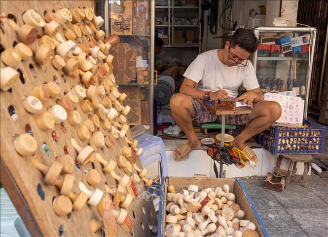 Tại phố Hàng Quạt, người thợ thủ công vẫn miệt mài làm con dấu phục vụ người dân và du khách. Ảnh: Hoàng Hiếu - TTXVN