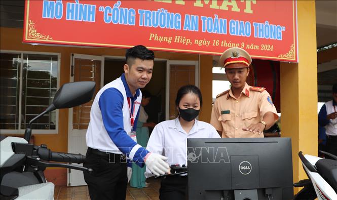 Cán bộ Đội Cảnh sát giao thông - trật tự (Công an huyện Phụng Hiệp) hướng dẫn học sinh lái xe an toàn bằng thiết bị mô phỏng. Ảnh: Hồng Thái - TTXVN