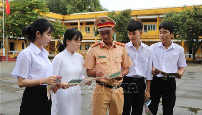 Cán bộ Đội Cảnh sát giao thông - trật tự (Công an huyện Phụng Hiệp) thực hiện tuyên truyền về Luật ATGT cho học sinh tại Trường THPT Hòa An. Ảnh: Hồng Thái - TTXVN