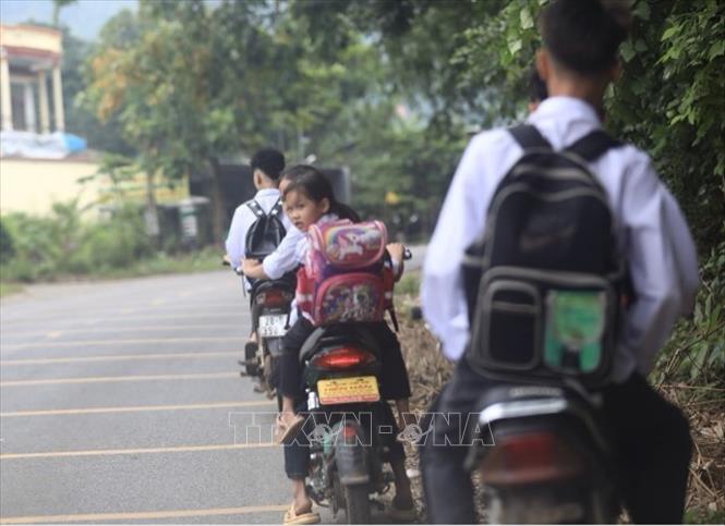 Hầu như học sinh sử dụng xe điện mà không thực hiện quy định đội mũ bảo hiểm. Ảnh: Hải Đat-TTXVN