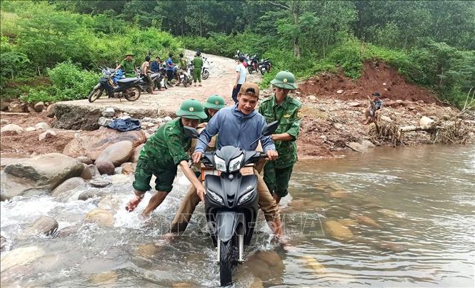 Cán bộ, chiến sỹ Đồn Biên phòng Ra Mai (Bộ đội Biên phòng Quảng Bình) hỗ trợ người dân, phương tiện đi qua các ngầm tràn, điểm giao thông đảm bảo an toàn. Ảnh: TTXVN phát