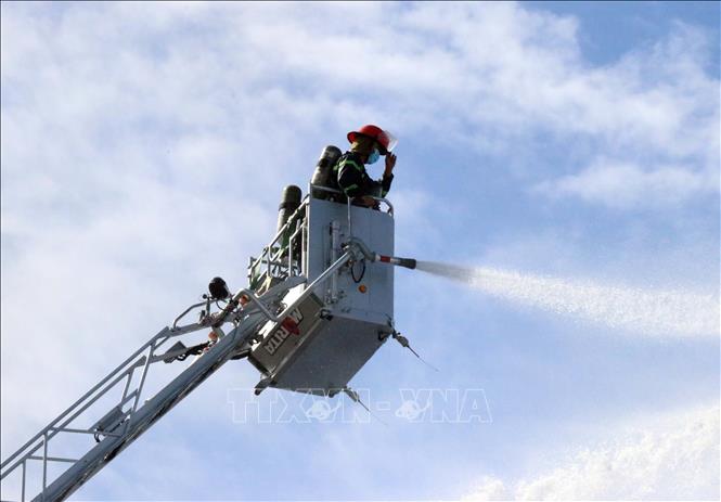 Lực lượng Cảnh sát Phòng cháy chữa cháy và cứu nạn, cứu hộ Công an tỉnh Ninh Thuận đứng trên hệ thống cẩu để phun nước xử lý đám cháy từ trên cao xuống. Ảnh: Công Thử - TTXVN