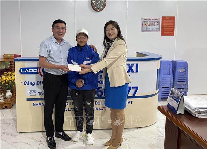 Bà Nguyễn Thị Giao, Giám đốc Chi nhánh taxi Lado Đà Lạt và nữ tài xế Phạm Thị Như Quỳnh (đứng giữa) trả lại số tiền cho khách hàng đánh rơi trên xe. Ảnh: TTXVN phát