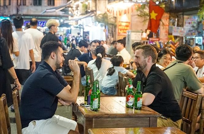 Du khách nước ngoài thích thú với việc thưởng thức ẩm thực tại phố Tạ Hiện. Ảnh: Khánh Hòa - TTXVN