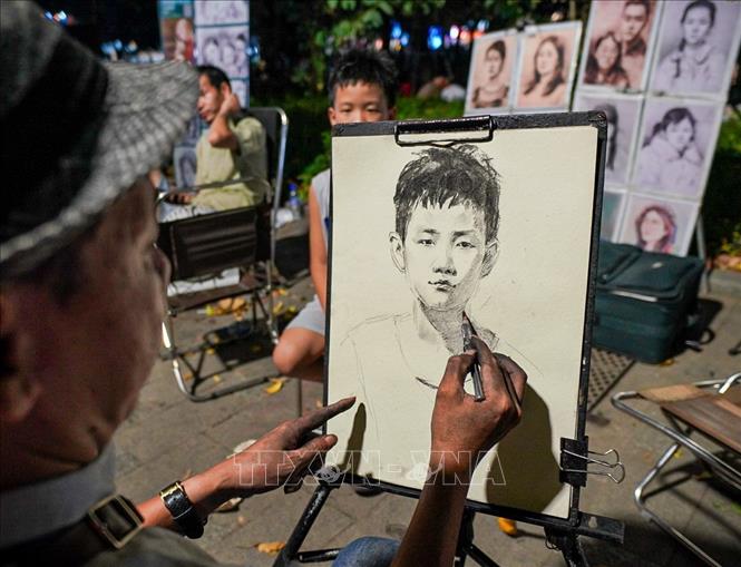 Vẽ tranh ký họa tại phố đi bộ hồ Hoàn Kiếm cũng là một hoạt động thu hút người dân và du khách. Ảnh: Khánh Hòa - TTXVN