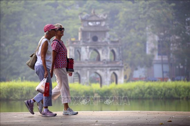 Du khách nước ngoài đi dạo bên hồ Hoàn Kiếm. Ảnh: Tuấn Đức - TTXVN