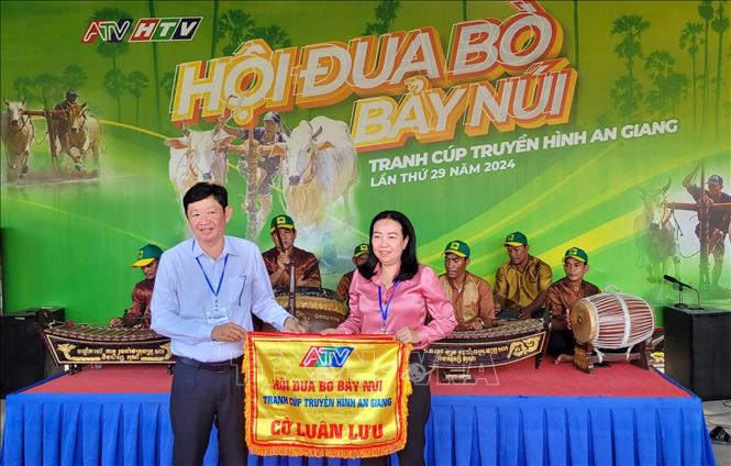Ông Lâm Văn Bá, Phó Chủ tịch UBND thị xã Tịnh Biên (trái) trao cờ đăng cai Hội đua bò Bảy Núi An Giang năm 2025 cho huyện Tri Tôn. Ảnh: Công Mạo-TTXVN