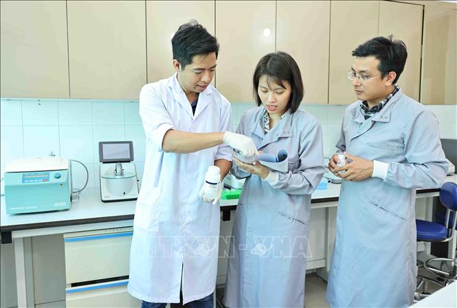 Tiến sĩ Sinh học Nguyễn Hữu Tiền trao đổi kinh nghiệm với đồng nghiệp trong phòng nghiên cứu tuyến trùng học. Ảnh: Minh Đức – TTXVN
