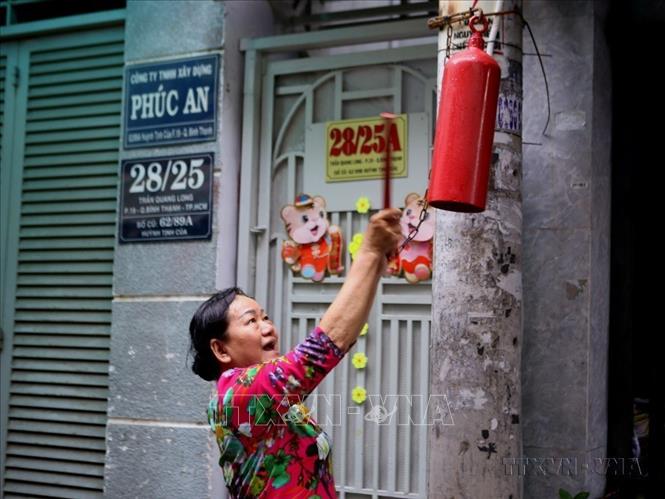 Bà Lai Kim Liêng, thành viên Tổ liên gia của Phường 19, thành phố Thủ Đức (Thành phố Hồ Chí Minh) gõ kẻng báo động hàng xóm trong tình huống cháy giả định. Ảnh: Thành Chung - TTXVN