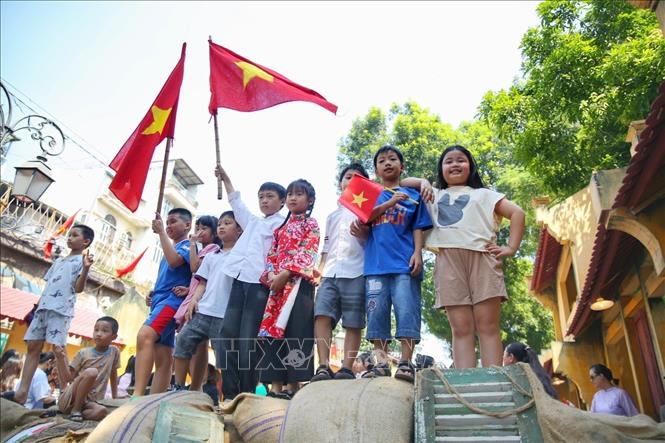 Các em nhỏ được bố mẹ chụp ảnh cùng Quốc kỳ. Ảnh: Tuấn Đức - TTXVN